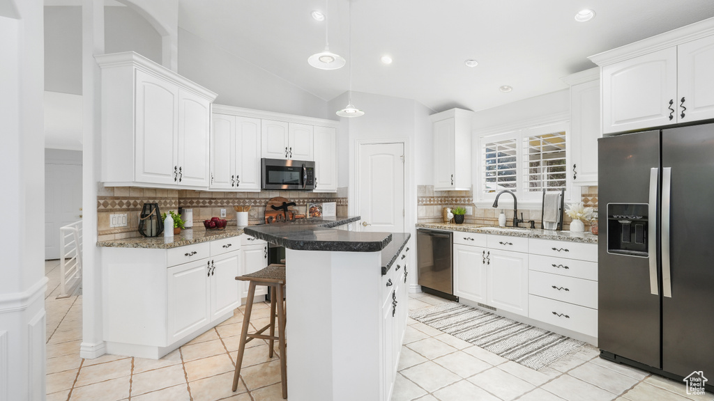 Kitchen featuring a kitchen island, a breakfast bar area, stainless steel appliances, white cabinetry, and backsplash