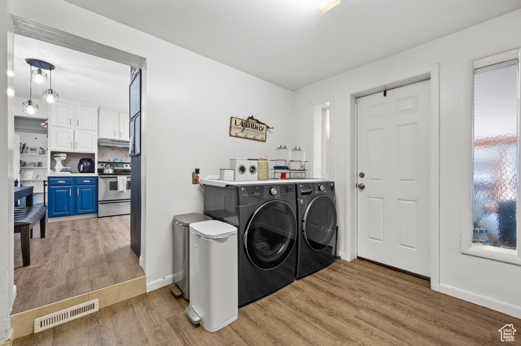 Laundry room with independent washer and dryer and hardwood / wood-style flooring