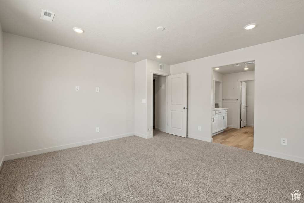 Unfurnished bedroom featuring light colored carpet and connected bathroom