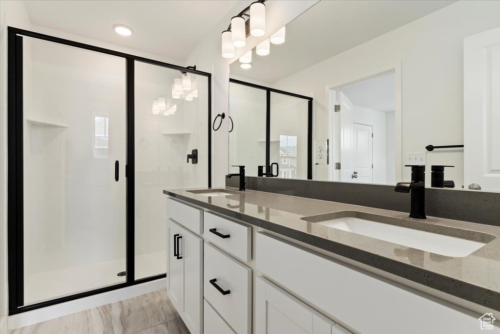 Bathroom featuring dual sinks, an enclosed shower, and large vanity