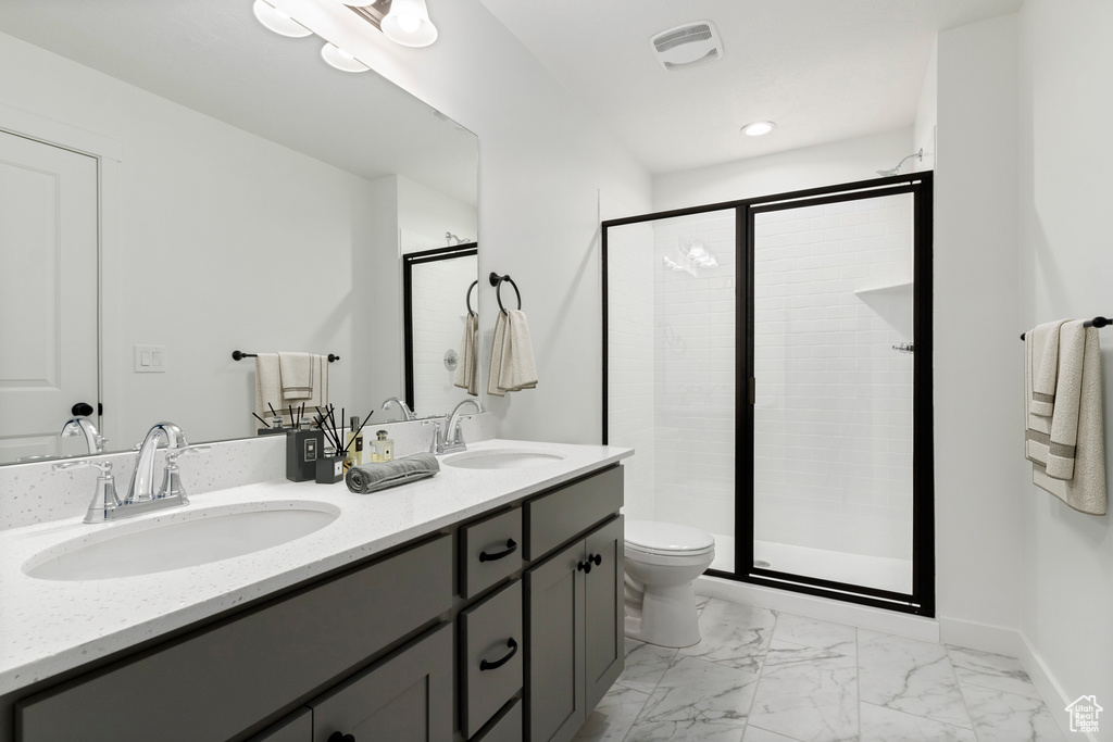Bathroom featuring tile flooring, oversized vanity, dual sinks, toilet, and walk in shower