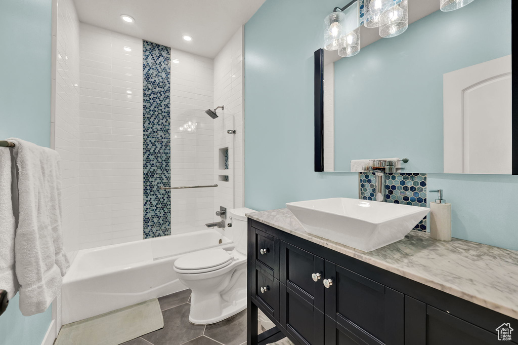 Full bathroom with vanity, toilet, tile floors, and tiled shower / bath