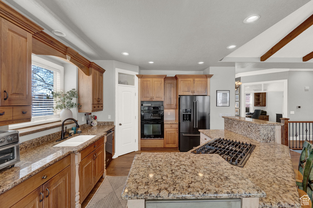 Kitchen with sink, a kitchen island, light stone counters, and stainless steel appliances