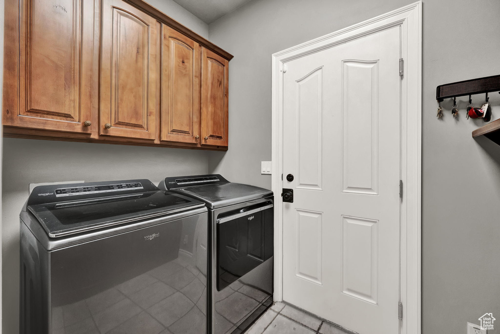 Washroom with cabinets, light tile flooring, and washer and dryer