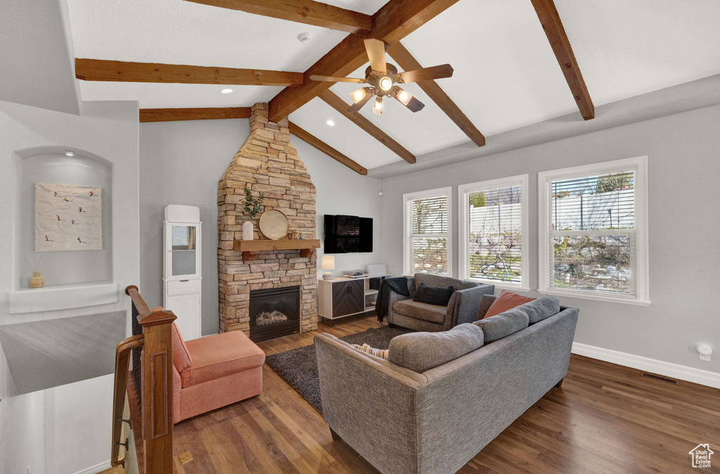 Living room featuring a fireplace, ceiling fan, dark hardwood / wood-style flooring, and beam ceiling