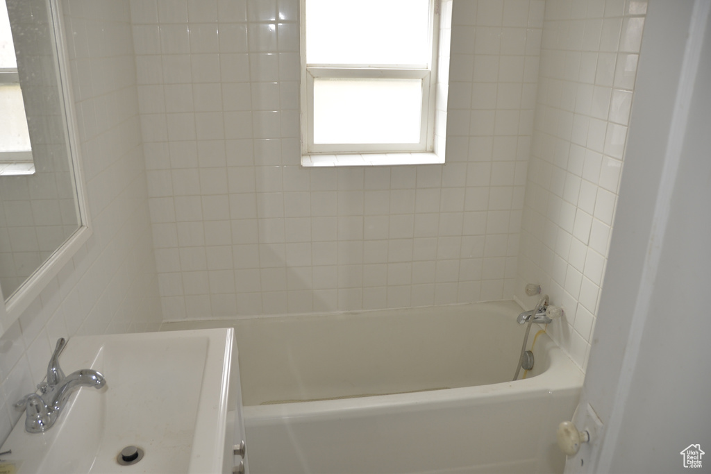 Bathroom with sink, tiled shower / bath combo, and tile walls