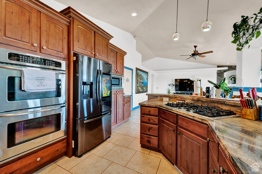Kitchen featuring ceiling fan, light stone counters, stainless steel appliances, and vaulted ceiling