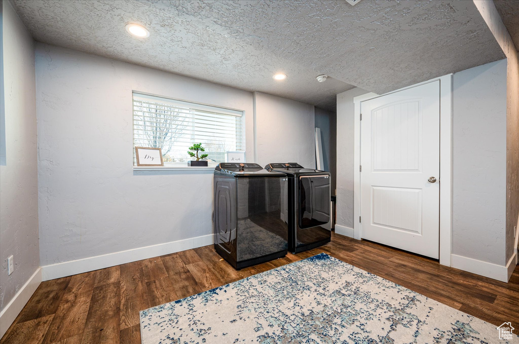 Interior space featuring a textured ceiling, washing machine and dryer, and dark hardwood / wood-style floors
