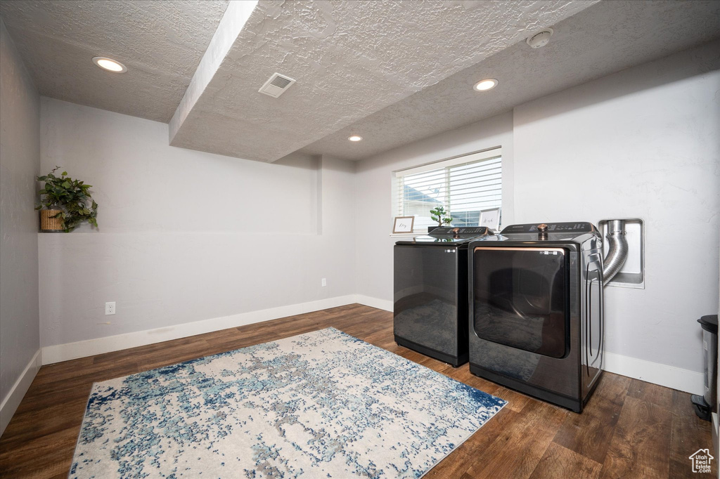 Laundry room featuring washing machine and dryer, dark hardwood / wood-style flooring, and a textured ceiling