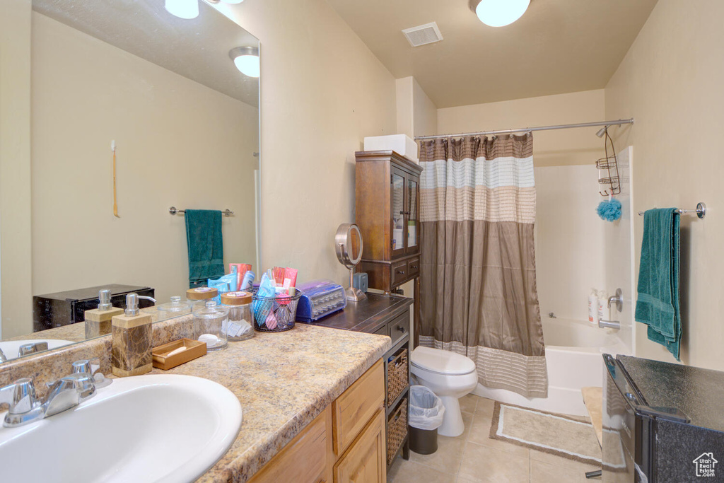 Full bathroom with tile flooring, shower / bath combo with shower curtain, toilet, and oversized vanity