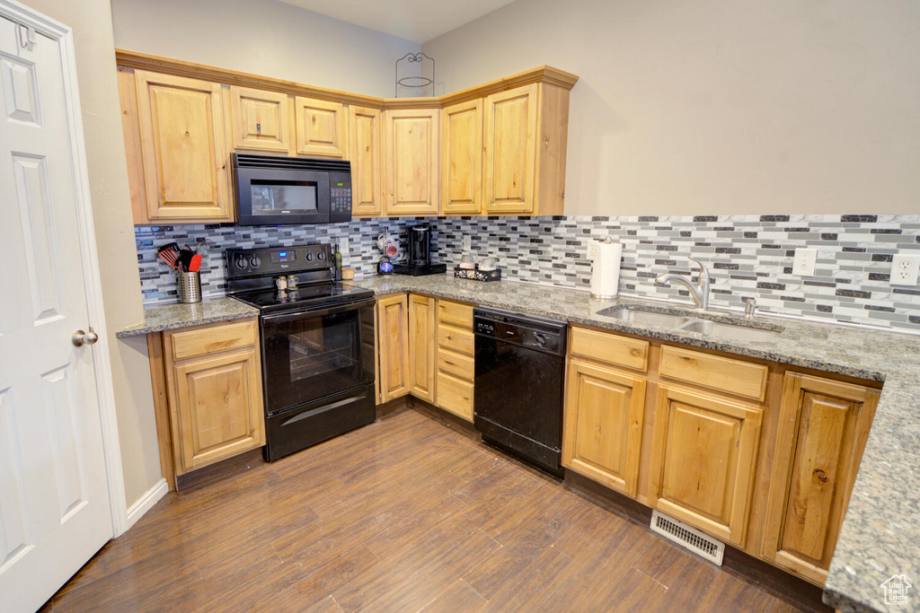 Kitchen with tasteful backsplash, sink, black appliances, and dark hardwood / wood-style floors