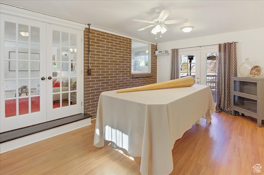 Bedroom with ceiling fan, access to exterior, french doors, light hardwood / wood-style floors, and brick wall