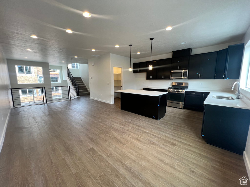 Kitchen featuring a center island, stainless steel appliances, decorative light fixtures, sink, and light hardwood / wood-style flooring