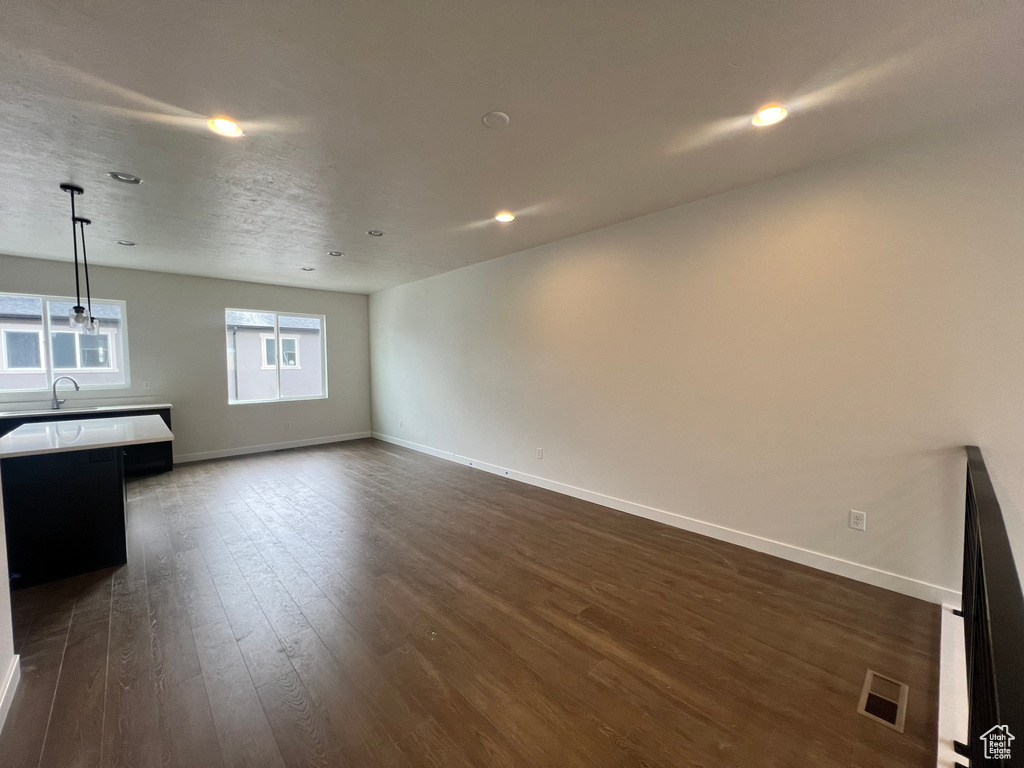 Unfurnished living room with sink and dark wood-type flooring