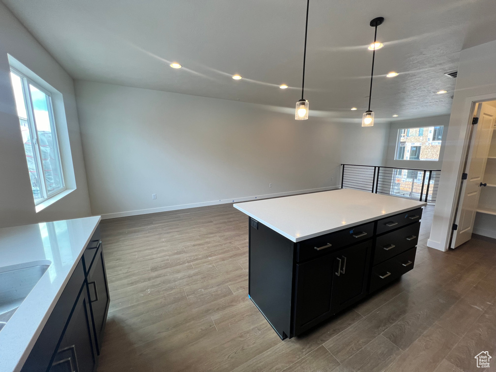 Kitchen with sink, wood-type flooring, a kitchen island, and decorative light fixtures