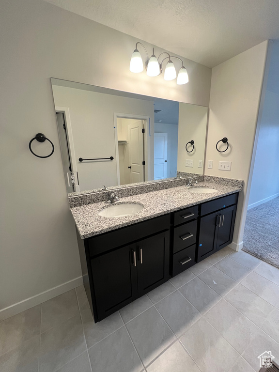 Bathroom featuring tile floors, vanity with extensive cabinet space, and dual sinks