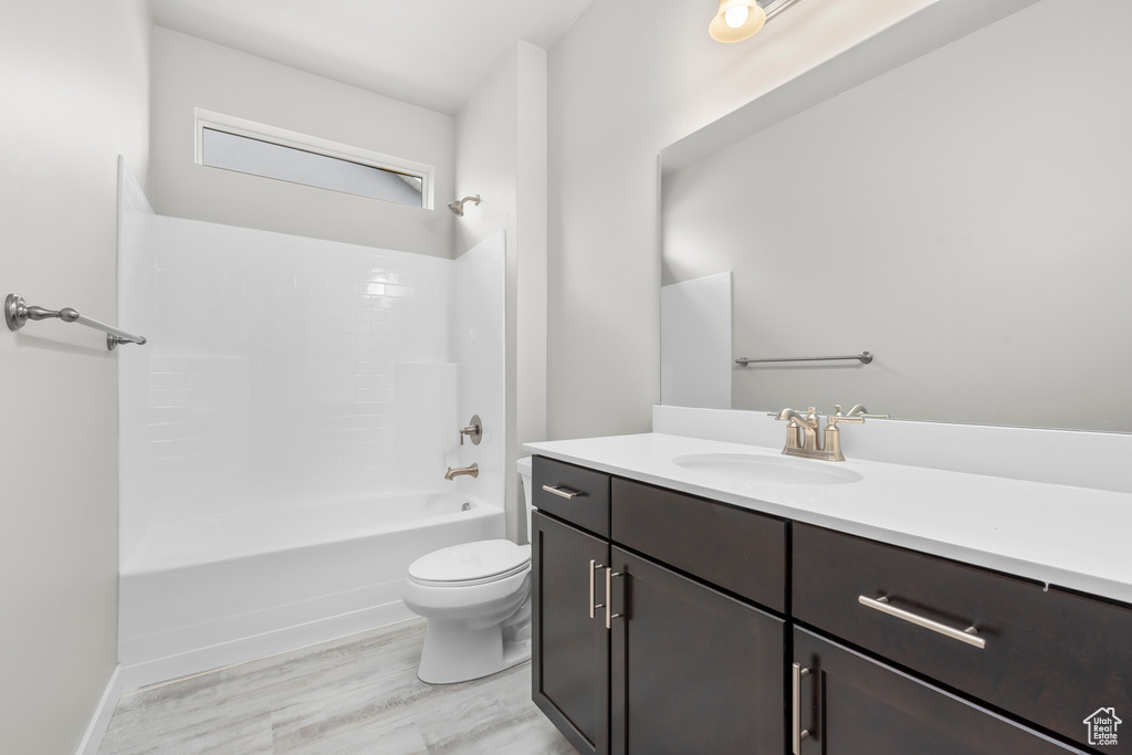 Full bathroom with hardwood / wood-style floors, vanity, shower / tub combination, and toilet