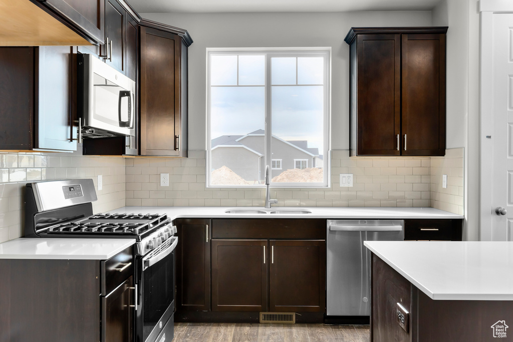 Kitchen featuring sink, a wealth of natural light, tasteful backsplash, appliances with stainless steel finishes, and light hardwood / wood-style floors