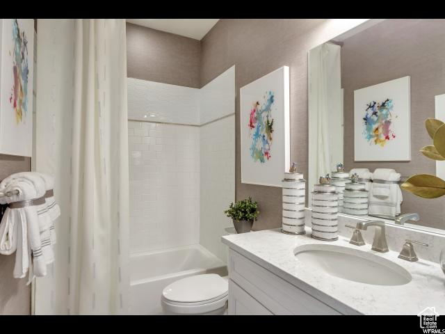 Full bathroom with shower / bath combination with curtain, vanity, and toilet
