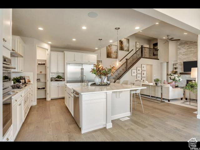 Kitchen with appliances with stainless steel finishes, hanging light fixtures, and white cabinetry