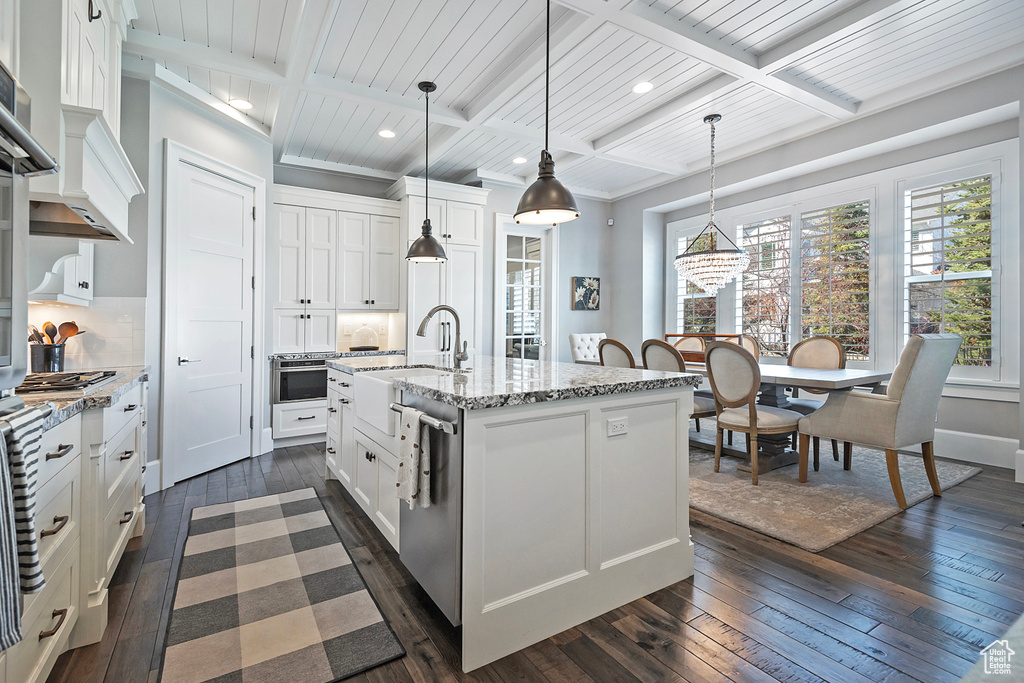 Kitchen with a center island with sink, coffered ceiling, and pendant lighting