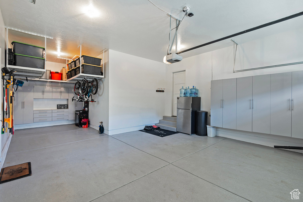 Garage with a garage door opener and stainless steel fridge