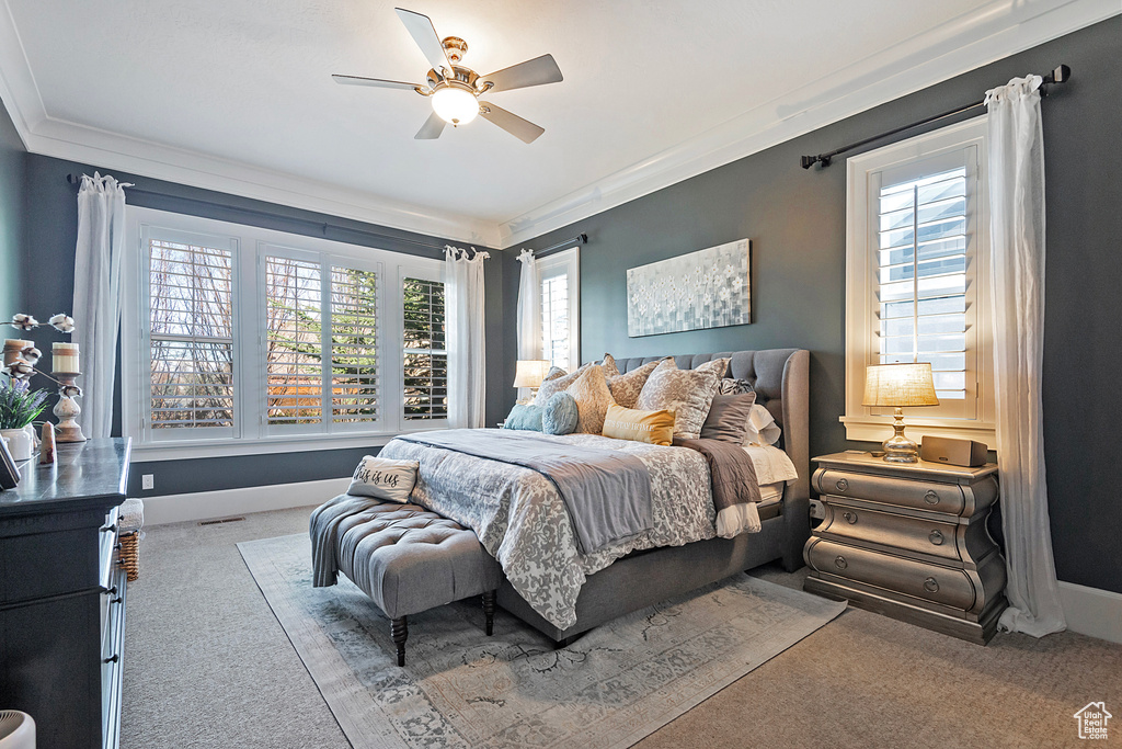 Carpeted bedroom with ceiling fan and ornamental molding