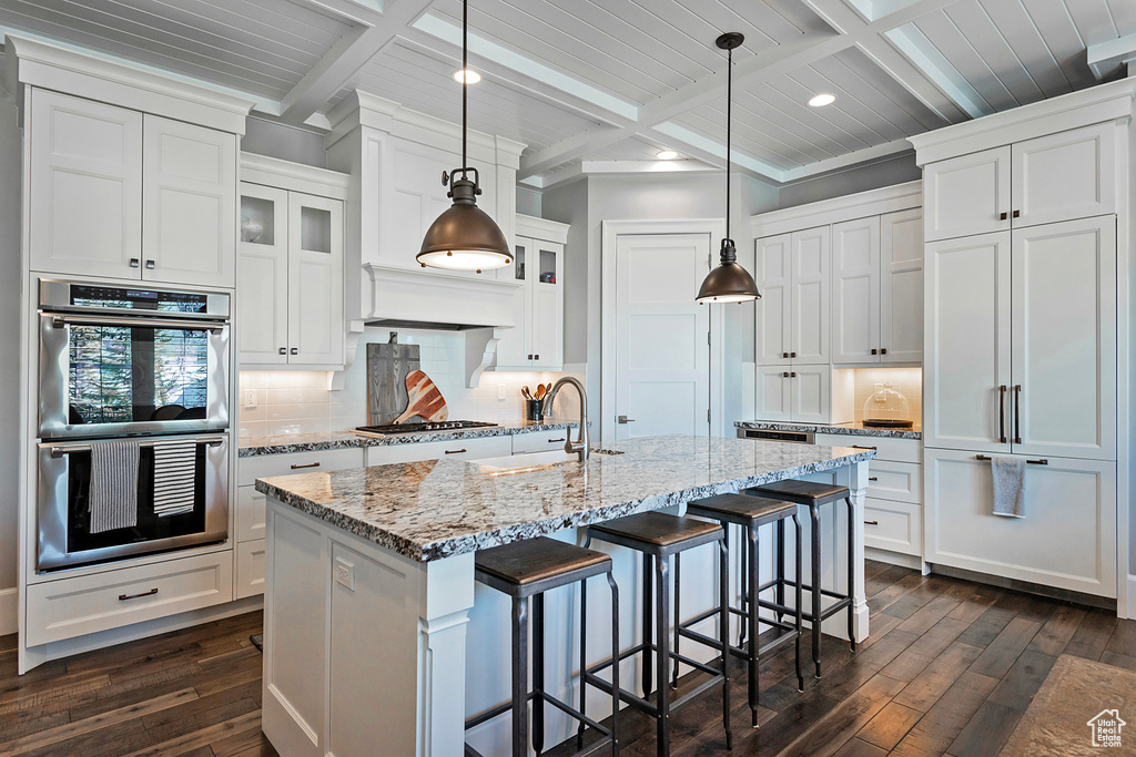 Kitchen with appliances with stainless steel finishes, decorative light fixtures, coffered ceiling, and beamed ceiling
