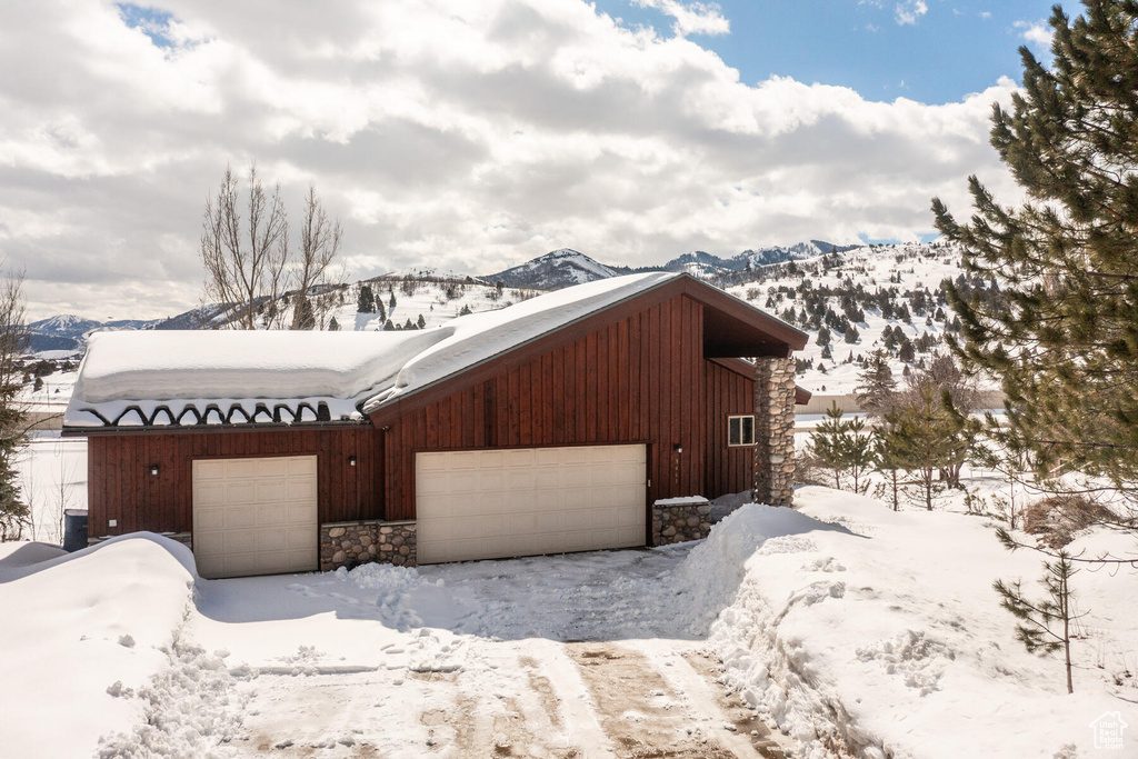 View of snow covered exterior with a mountain view and a garage