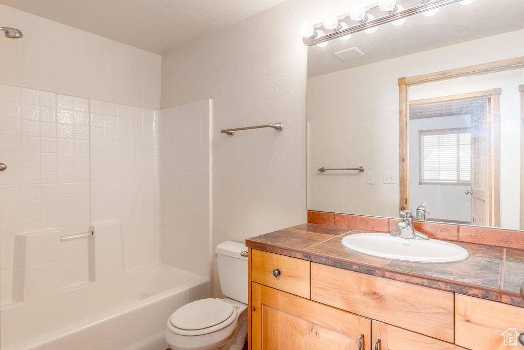 Full bathroom with toilet, shower / bathing tub combination, and vanity with extensive cabinet space