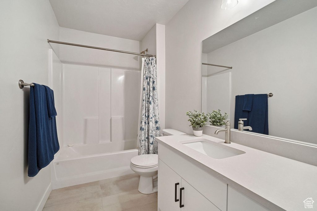 Full bathroom featuring shower / tub combo with curtain, toilet, tile flooring, and vanity with extensive cabinet space