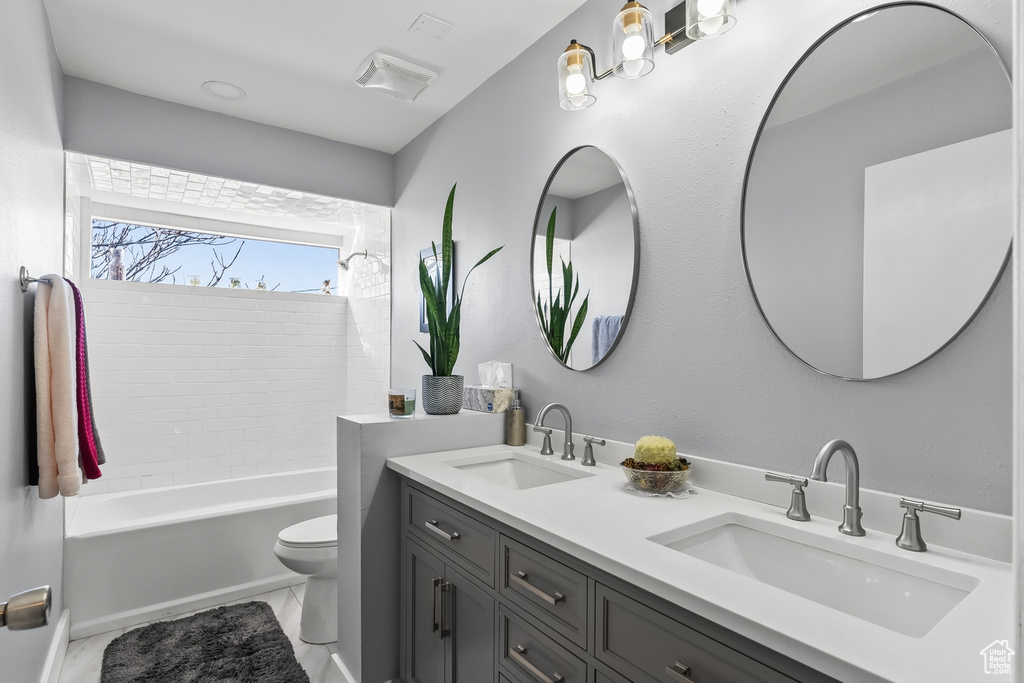 Full bathroom featuring double sink vanity, toilet, tile flooring, and bathtub / shower combination
