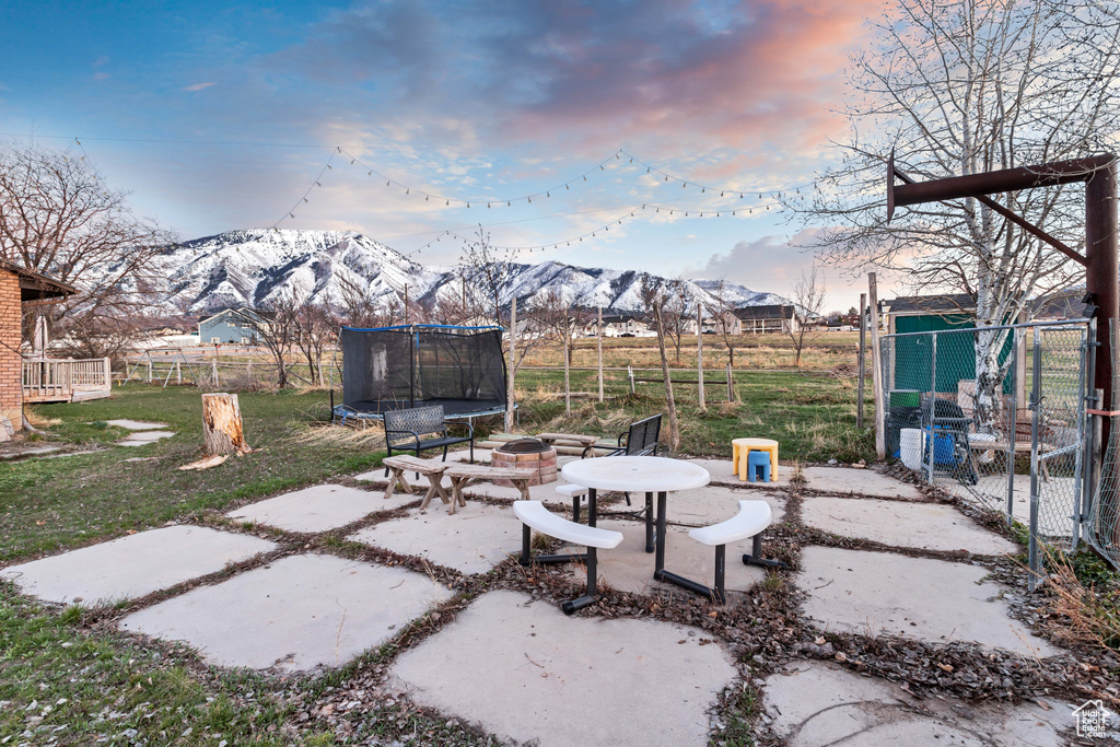 View of terrace with an outdoor fire pit, a mountain view, and a trampoline