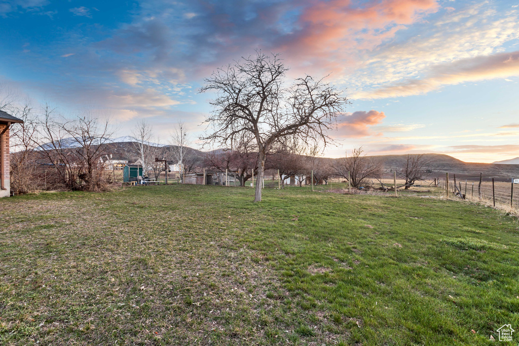 Yard at dusk featuring a mountain view and a rural view