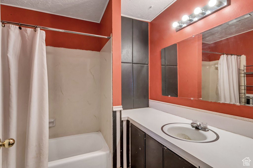 Bathroom featuring shower / tub combo, a textured ceiling, and oversized vanity