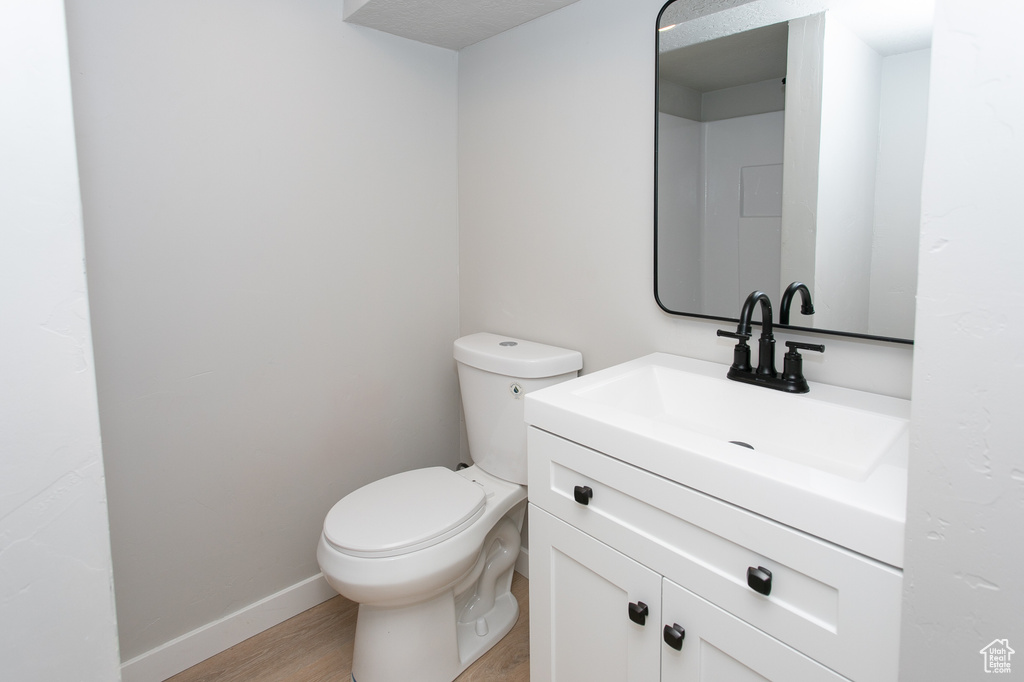 Bathroom with hardwood / wood-style floors, vanity, and toilet