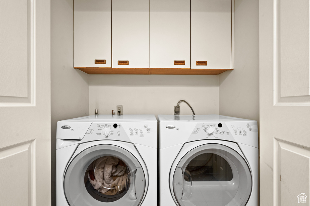 Laundry area featuring electric dryer hookup, washer and clothes dryer, and cabinets
