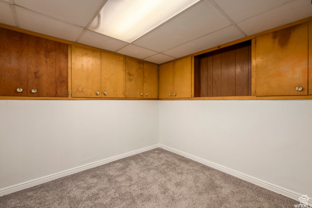 Basement with a paneled ceiling and carpet floors