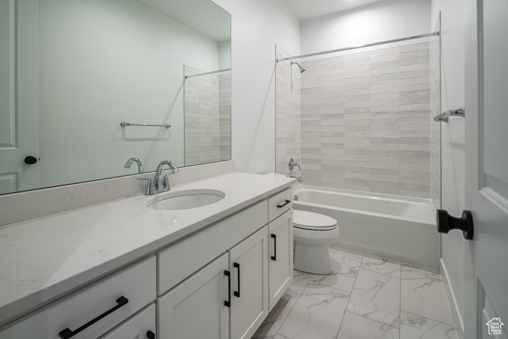 Full bathroom featuring vanity with extensive cabinet space, toilet, tile floors, and tiled shower / bath combo