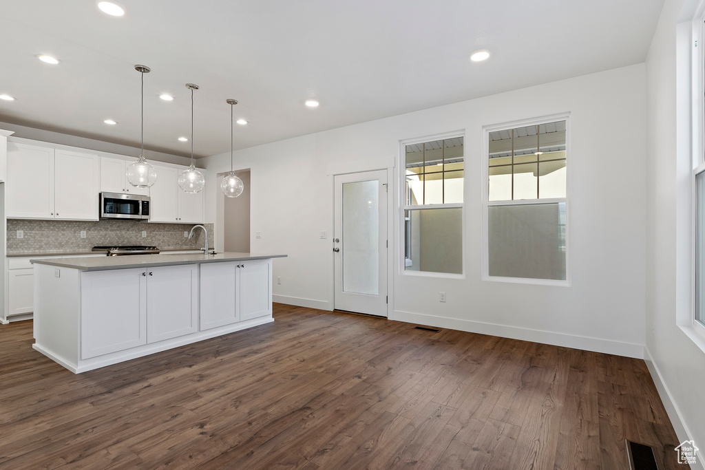 Kitchen featuring white cabinetry, a kitchen island with sink, tasteful backsplash, and dark hardwood / wood-style floors