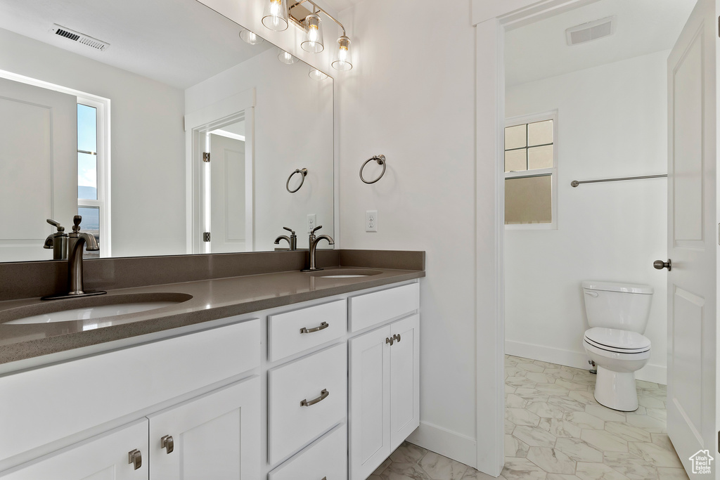 Bathroom with double sink vanity, toilet, and tile floors
