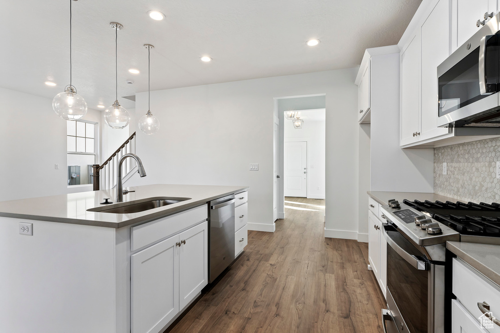 Kitchen featuring backsplash, white cabinets, stainless steel appliances, dark hardwood / wood-style floors, and sink