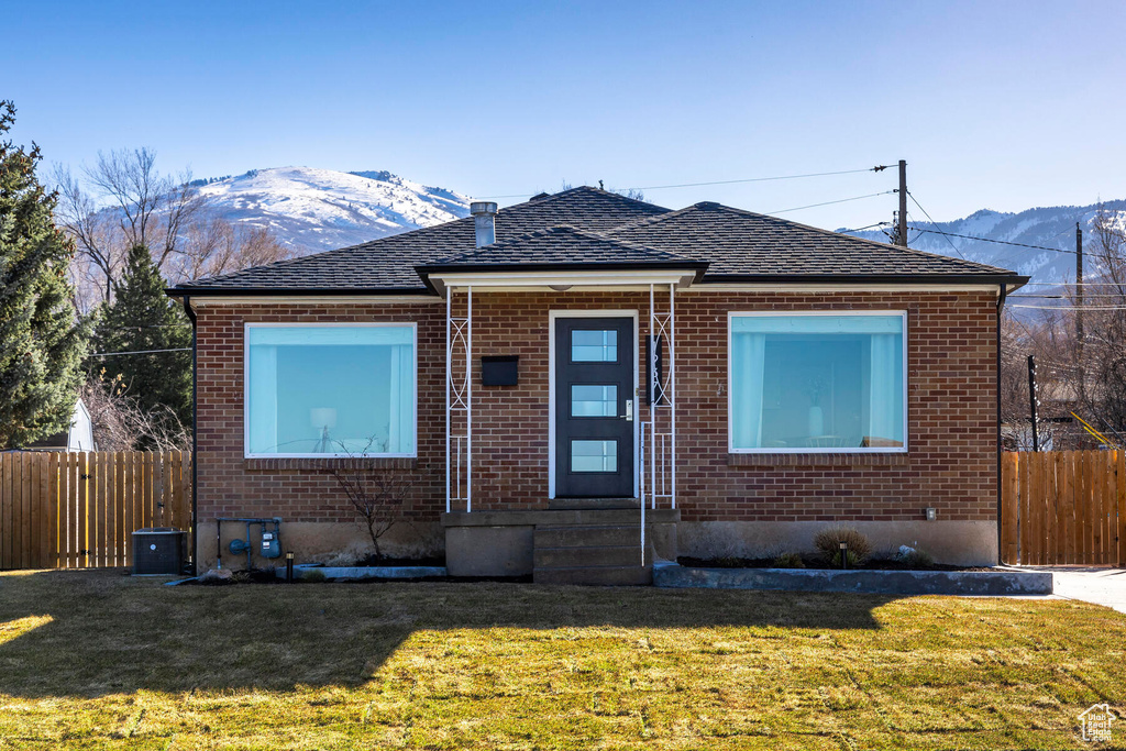 Bungalow-style house featuring central air condition unit, a front lawn, and a mountain view