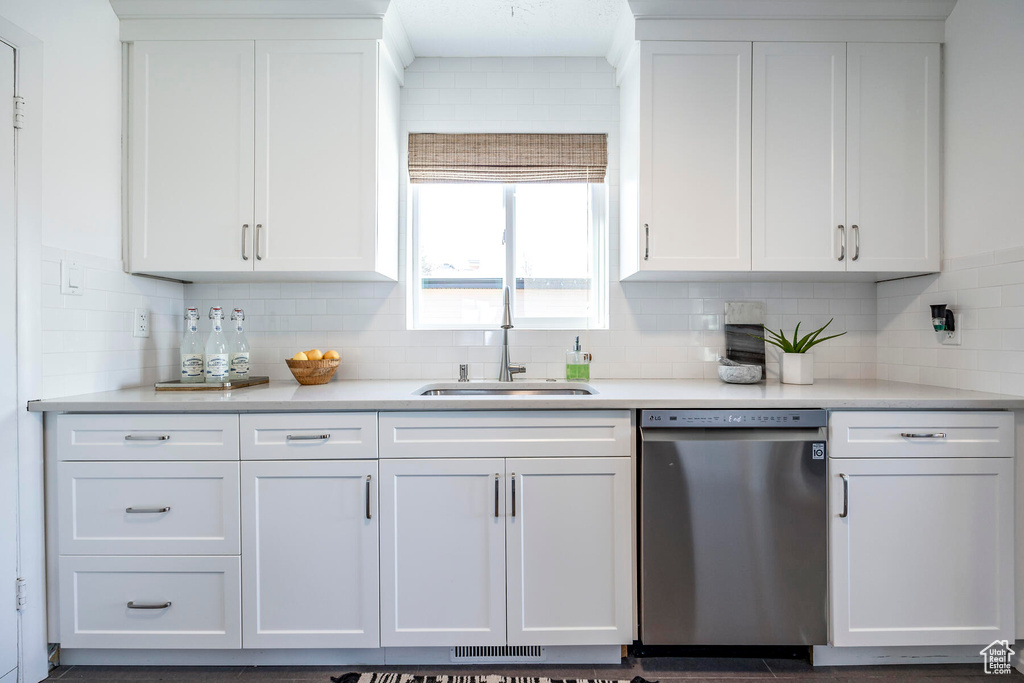 Kitchen with tasteful backsplash, sink, white cabinets, and stainless steel dishwasher