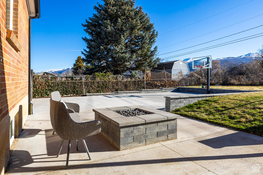 View of patio / terrace featuring an outdoor fire pit, a mountain view, and basketball hoop