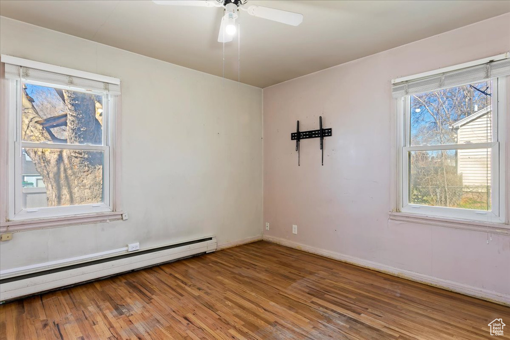 Empty room with baseboard heating, ceiling fan, and light hardwood / wood-style flooring