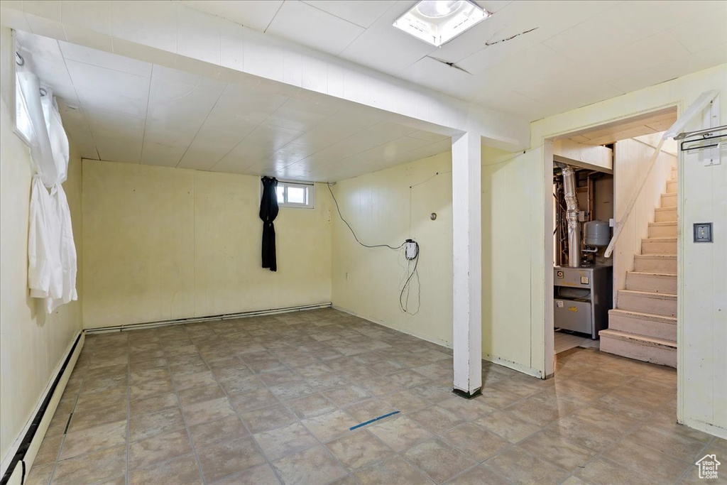 Basement with a baseboard heating unit and light tile flooring