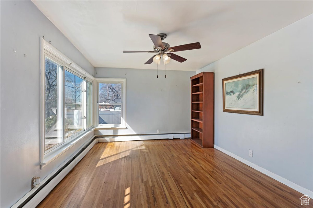 Spare room with dark wood-type flooring, baseboard heating, and ceiling fan