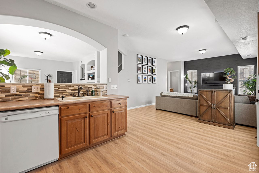 Kitchen featuring sink, light hardwood / wood-style flooring, tasteful backsplash, and dishwasher