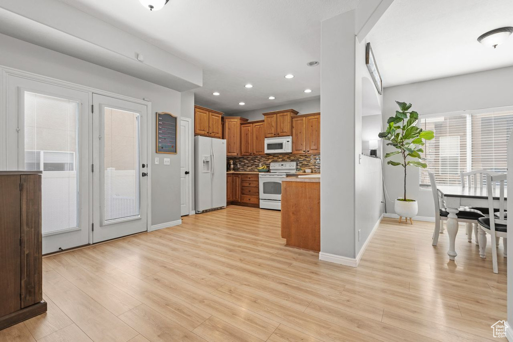 Kitchen featuring tasteful backsplash, white appliances, and light hardwood / wood-style flooring